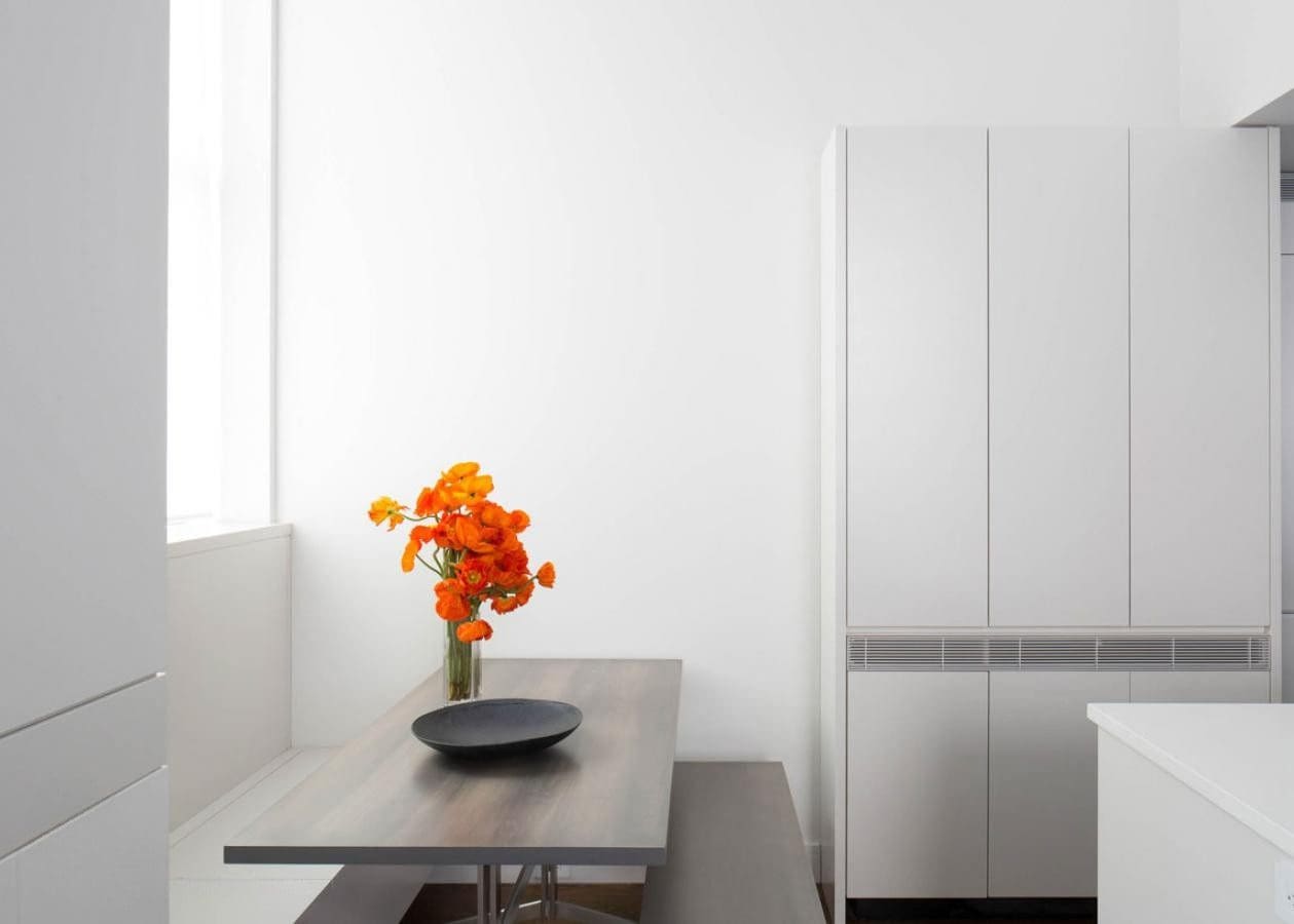 Minimalist room with bright orange flowers on a wooden table.